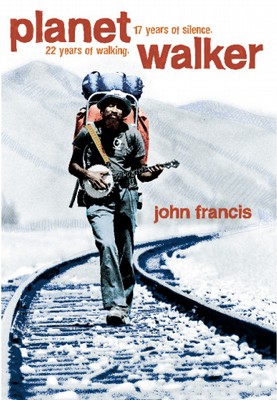 young black male environmentalist wearing a backpack and holding a banjo walking on railroad tracks in countryside.